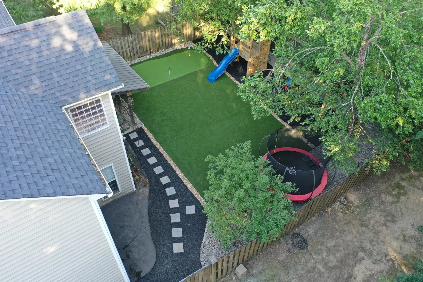Aerial view of a backyard with new artificial turf and stepping stones