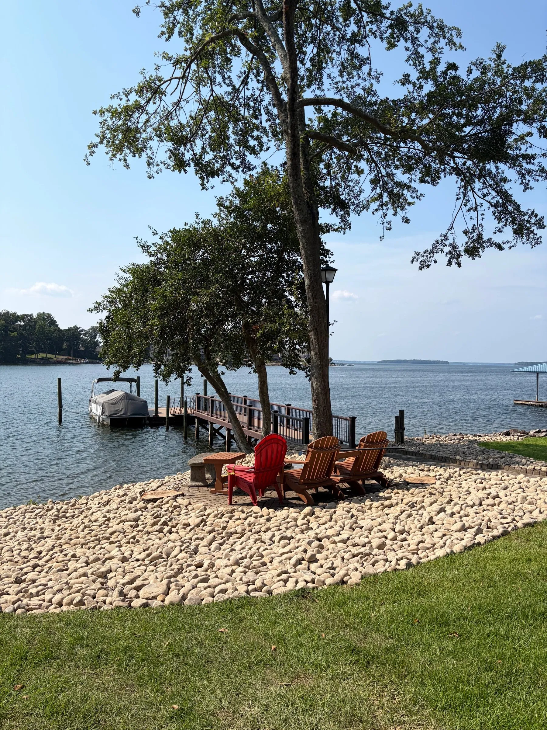 Lakefront yard with fresh river rock and Adirondack chairs overlooking the water
